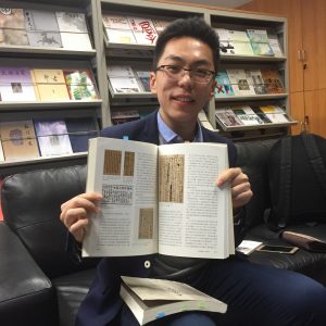 Graduate student Wei Haoyu holding one of his own published articles