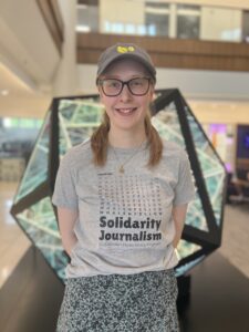 a female student posing in front of an art piece in schoenecker center