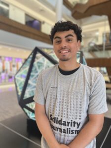 a male student posing in front of an art piece