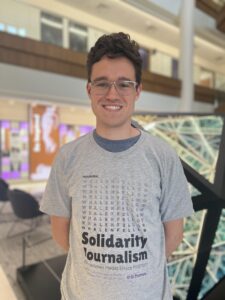 a male student posing in front of an art piece