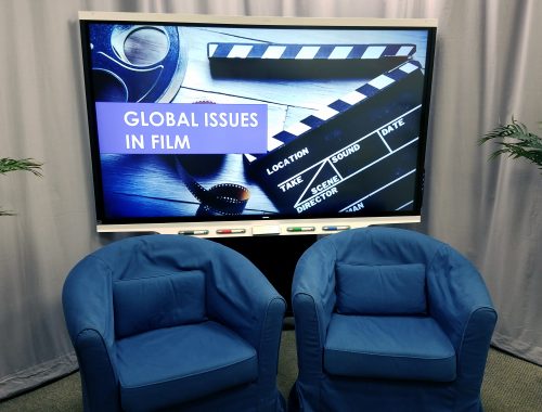 Image showing an example of the studio set up with the SMART Board lowered behind chairs displaying a backdrop of film and a title, two chairs and ferns