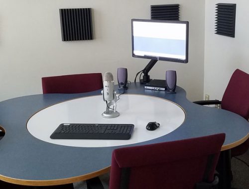 Podcast studio with microphone, table, and four chairs