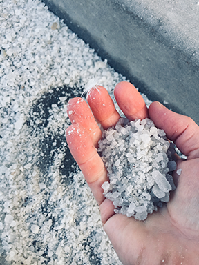 Image of a handful of road salt on a sidewalk